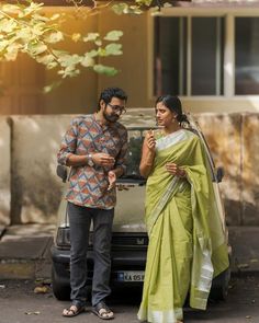 a man and woman standing next to a car