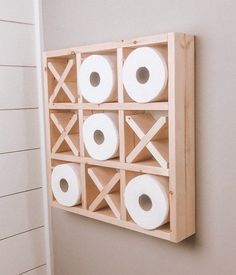 three rolls of toilet paper are mounted on the wall above a wooden box with holes in it