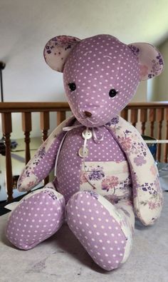 a purple teddy bear sitting on top of a wooden table next to a banister