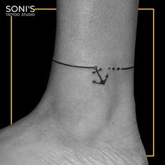 a black and white photo of a small anchor on the ankle tattoo design by soni's tattoo studio