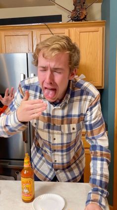 a young man making a face with his mouth wide open in front of a refrigerator