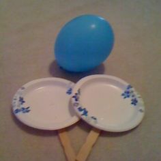 two paper plates with blue flowers on them are next to a plastic ball and toothpicks