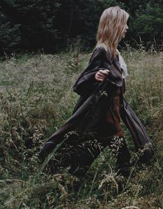 a woman is walking through the tall grass