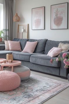 a living room with grey couches and pink accents on the walls, rugs and tables