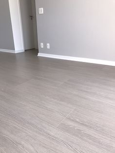 an empty room with white walls and wood flooring is seen in this image from the doorway