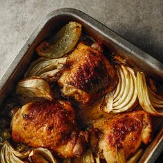 a pan filled with chicken and onions on top of a table