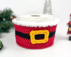 a crocheted santa's sleigh is next to a roll of toilet paper