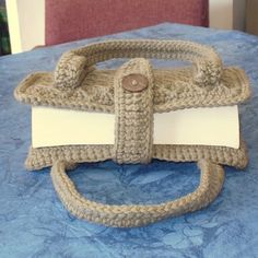 a crocheted purse sitting on top of a blue bed covered in a blanket