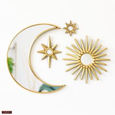 two gold sun and moon wall hangings on a white wall next to a mirror