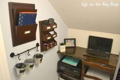 a desk with a laptop and other items on it in the corner of a room