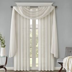 a living room with white curtains and a chair