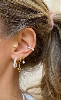 a close up of a person wearing ear piercings with pearls and gold beads on them