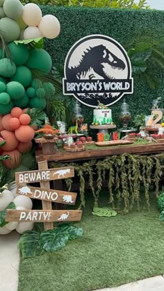 a dinosaur themed party with balloons and desserts in the shape of animals, plants and trees