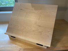 a wooden box sitting on top of a hard wood floor in front of a window