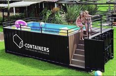 two women in pink swimsuits standing next to an above ground pool with balls on the grass