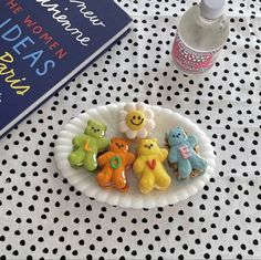 four teddy bears are sitting on a plate next to a book and bottle of water