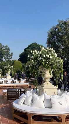 an outdoor seating area with white pillows and flowers