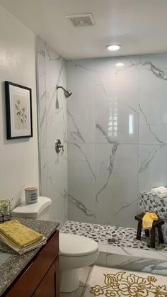 a bathroom with a toilet, sink and shower in it's own area that has marble tiles on the walls