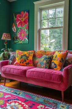 a pink couch sitting in front of a window with colorful pillows on top of it