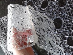 a hand holding a plastic container with water droplets on the glass and black surface behind it