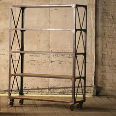 a metal and wood shelf sitting in front of a brick wall next to a wooden floor