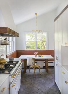 a kitchen with an oven, table and chairs in it