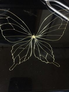 a close up of a butterfly on a glass surface with wires attached to the wings