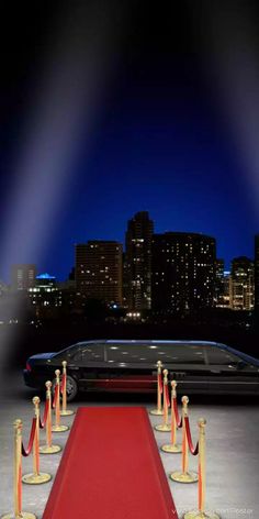 a long red carpeted path leading to a limo in front of a city at night