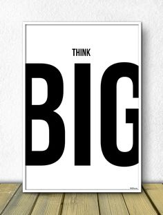 a black and white poster with the words think big on it in bold font, against a wooden floor