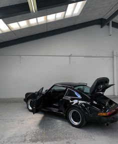 a black car parked in a garage with its hood open and it's door open