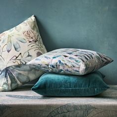 three pillows stacked on top of each other in front of a blue wall with leaves