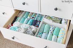 an organized drawer filled with folded towels and cloths on top of a carpeted floor