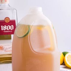 a pitcher of lemonade with limes around it