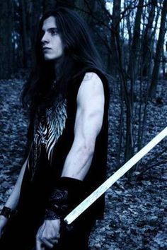 a man with long hair holding two swords in his hands while standing in the woods