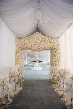 the entrance to a wedding ceremony with white flowers and chandelier hanging from the ceiling