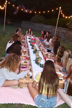 a group of women sitting at a long table with plates of food in front of them