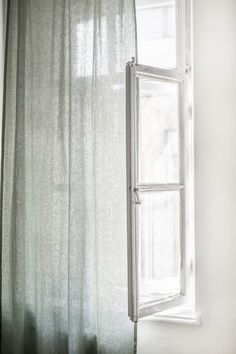 an open window sitting next to a white curtain