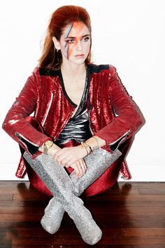 a woman sitting on top of a wooden floor with her legs crossed and painted red