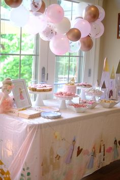 a table topped with lots of cake and balloons