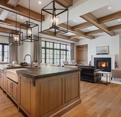 a large open concept kitchen and living room with wood flooring, white walls and ceiling beams