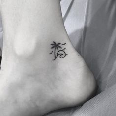 a small tattoo on the foot of a person with a palm tree and waves in the background