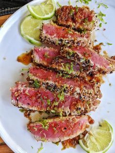 some meat is on a white plate with limes