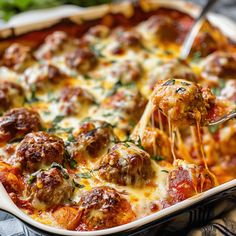 a close up of a casserole dish with meatballs being lifted from the casserole