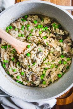 a pot full of rice and peas with a wooden spoon in it on a table