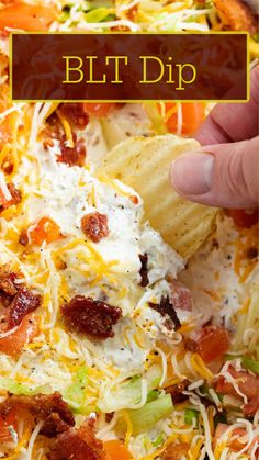 a hand holding a tortilla chip with bacon, cheese and lettuce