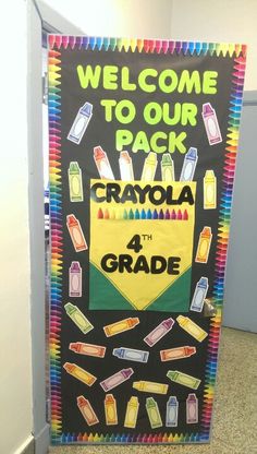 a welcome to our school sign with crayons and chalk markers on it in front of a door