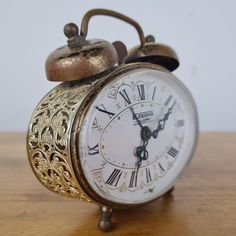 an antique clock with roman numerals on a wooden table