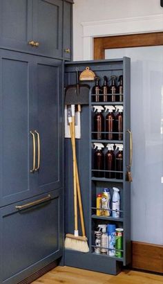 an open cabinet with cleaning supplies and brooms in the bottom section, next to a wooden floor