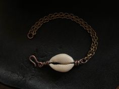 "This beautiful cowrie shell is wire wrapped with pure organic copper. The chain is vintage stock and made of solid brass. The metals have been oxidized for a rustic / tribal feel. All jewelry from my studio is endowed with a lifetime craftsmanship guarantee & arrives attractively packaged and ready for gifting or keeps. MEASUREMENTS & SPECIFICS: LENGTH: 7.25\" can be adjusted upon request METAL: solid vintage brass chain w/ hand forged copper hook / wire wrapping GEMSTONE: cowrie shell Bohemian Brass Bracelets With Adjustable Chain, Handmade Copper Jewelry For Beach, Handmade Copper Jewelry For The Beach, Bohemian Metal Shell Jewelry, Artisan Shell Jewelry With Adjustable Fit, Artisan Adjustable Shell Jewelry, Beach Wire Wrapped Metal Jewelry, Bohemian Wire Wrapped Shell Jewelry, Bohemian Shell-shaped Brass Jewelry