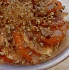 a bowl filled with carrots and nuts on top of a white tablecloth covered table